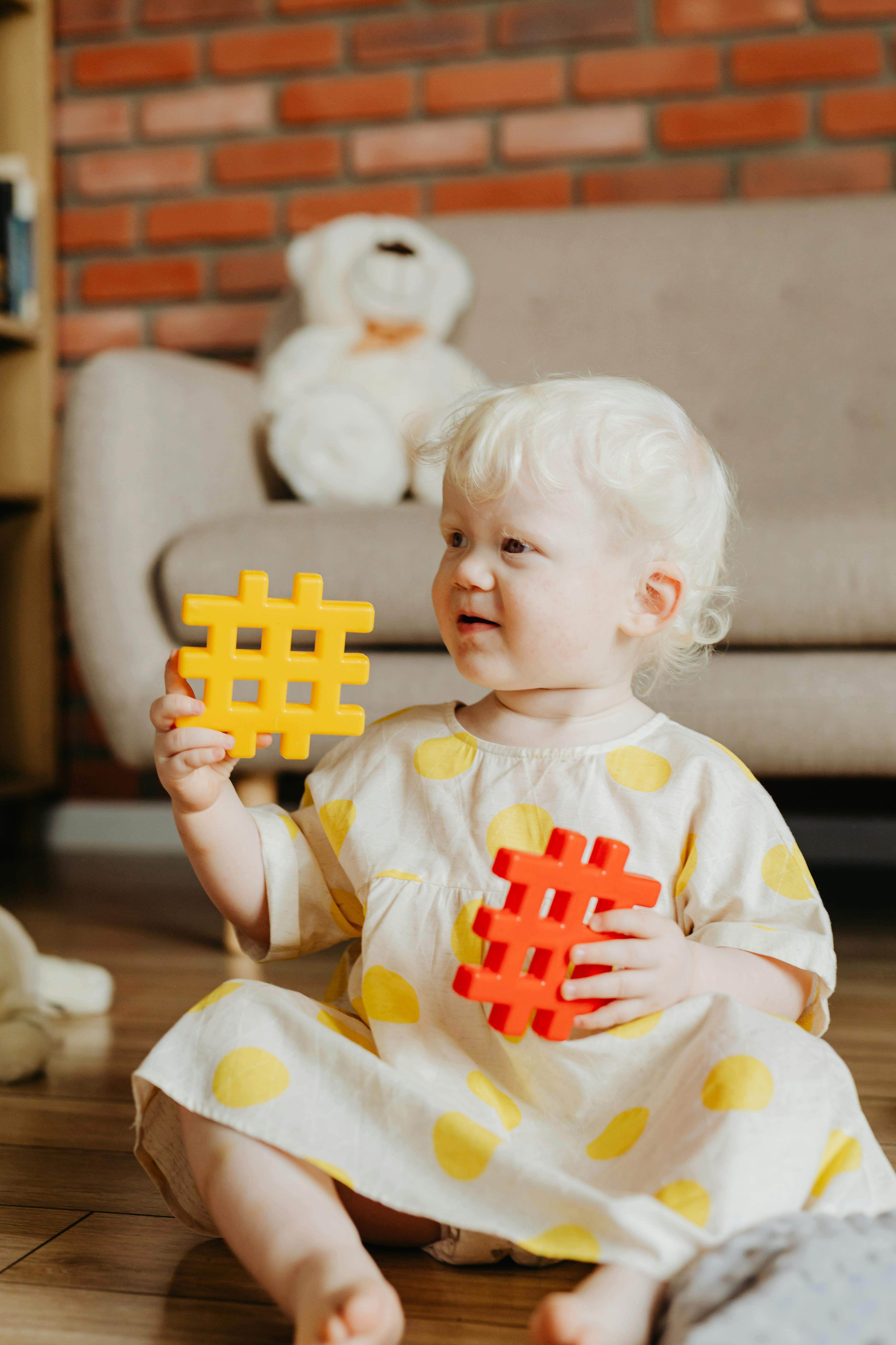 a baby girl sitting on floor holding building blocks