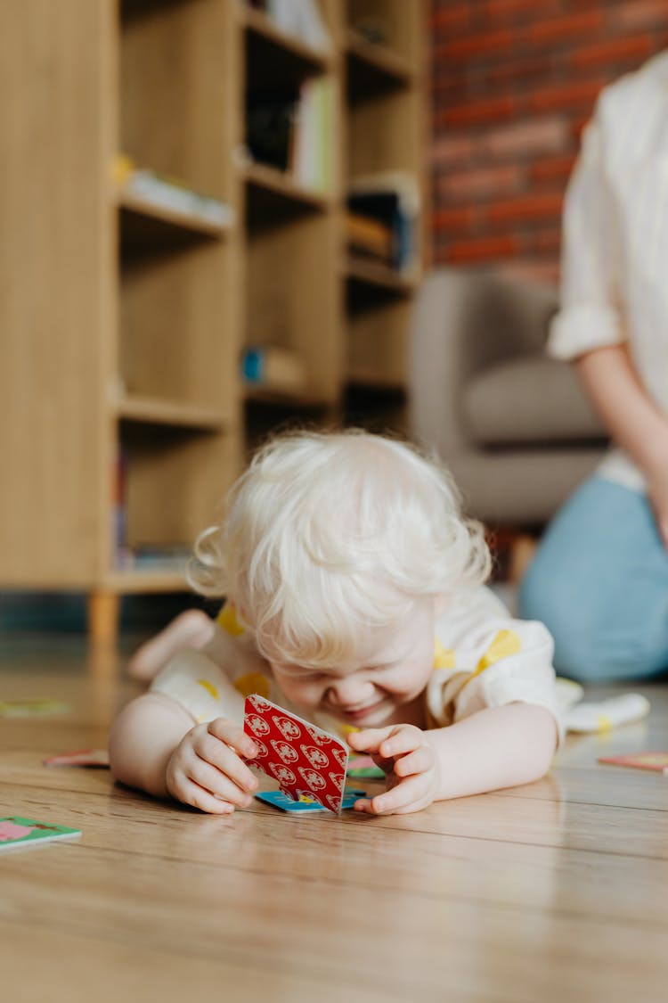 A Child Lying On The Floor While Playing 