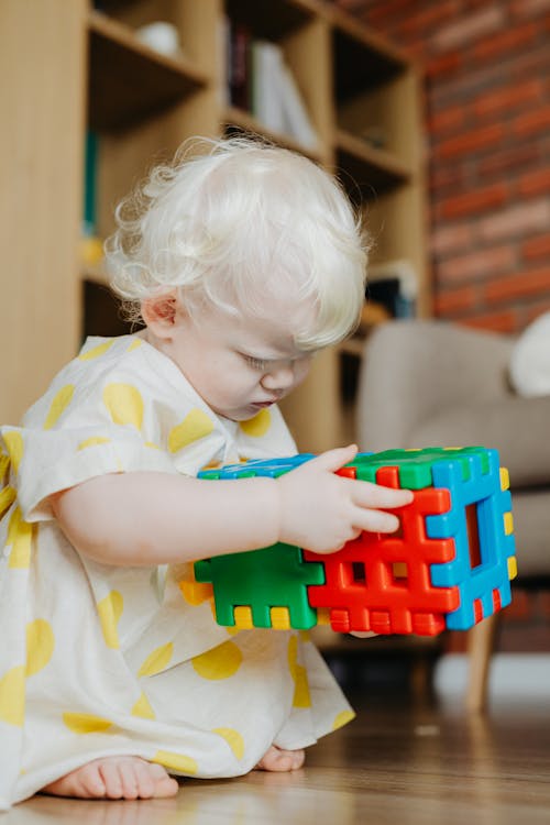 Close-Up Shot of a Cute Baby Girl Holding Plastic Toys
