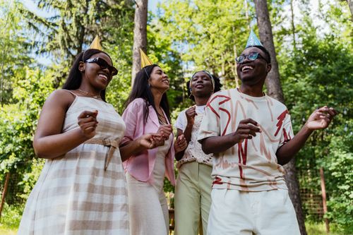 Free A group of diverse friends enjoying an outdoor party with party hats and smiles. Stock Photo