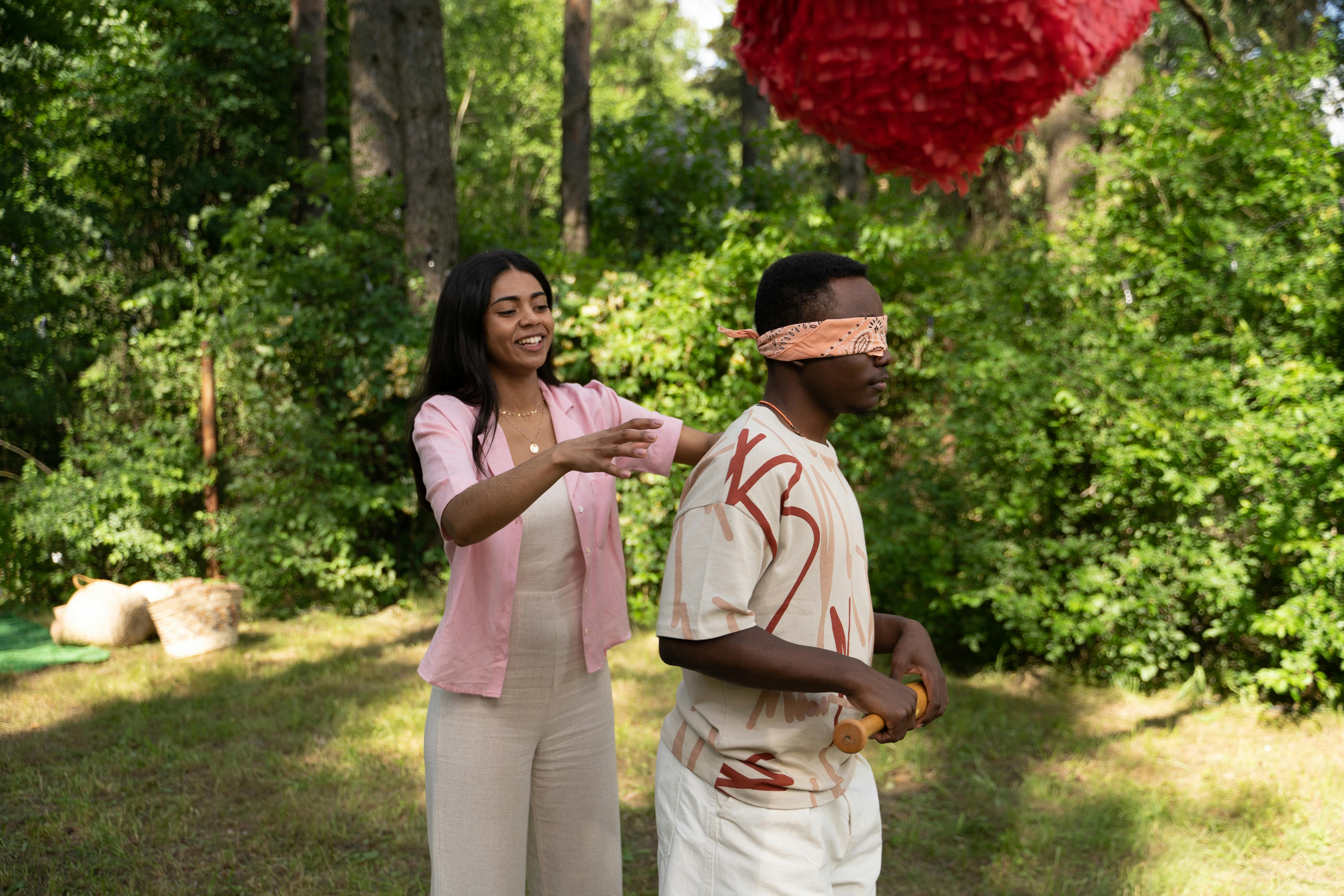 a young woman standing behind a man with a blind fold