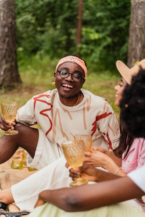 Free Joyful friends sharing wine at a relaxed outdoor picnic. Stock Photo