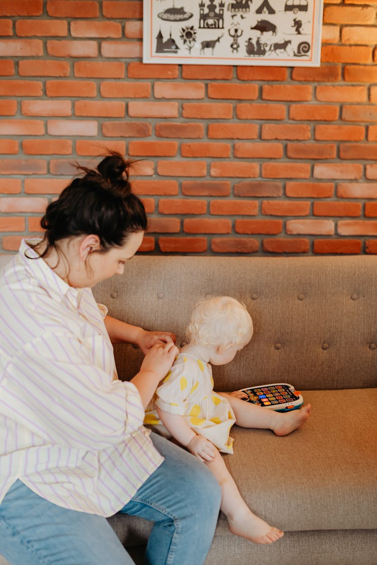 Woman Sitting On Brown Couch With Her Baby