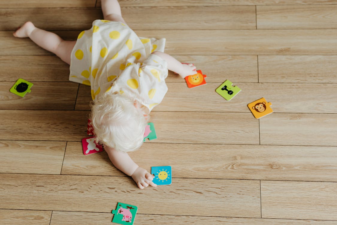 Free A Toddler Playing with Puzzle Pieces on the Floor Stock Photo