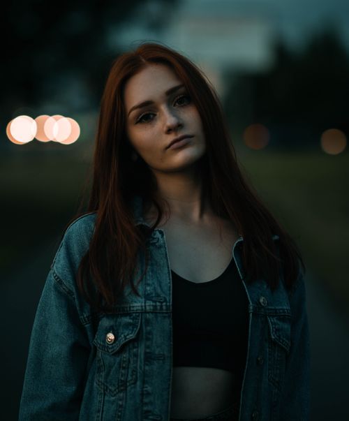 Free Moody outdoor portrait of a woman with long hair wearing a denim jacket, during twilight. Stock Photo