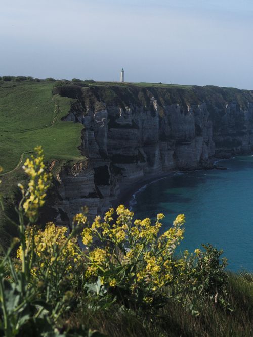 Free Dramatic cliffs with a lighthouse overlooking the ocean in Normandy, France, on a clear day. Stock Photo