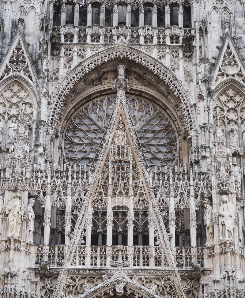 Extremely detailed Gothic facade of Rouen Cathedral showing stone carvings, rose window and arched portals