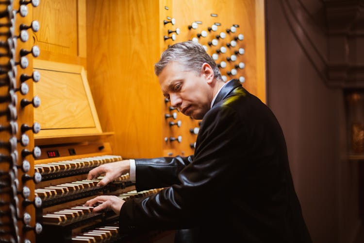 A Man In Black Leather Jacket Playing An Organ Piano