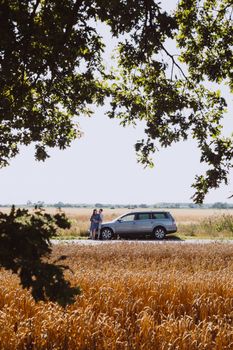 Couple enjoying a summer road trip with scenic countryside views.