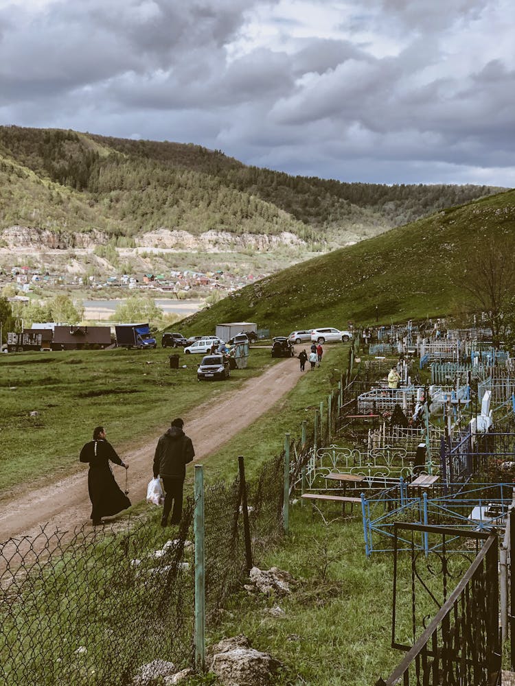 People Visiting A Cemetery In The Countryside