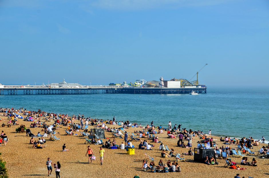 People enjoying a sunny day on Brighton Beach with a view of the iconic pier.