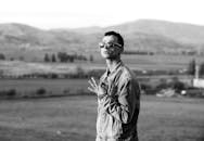 在山区背景下，时尚的年轻人穿着牛仔夹克自信地摆出姿势