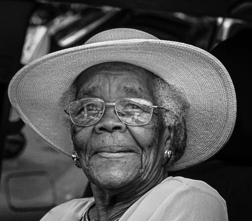 Free Black and white portrait of an elderly woman with glasses and a hat, showcasing wisdom and grace. Stock Photo