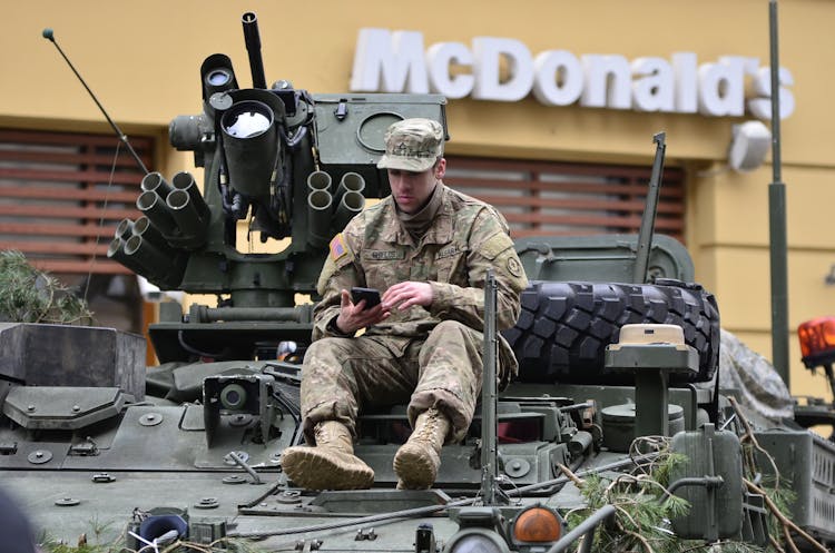 Man In Brown Camouflage Sitting On Top Of Tank