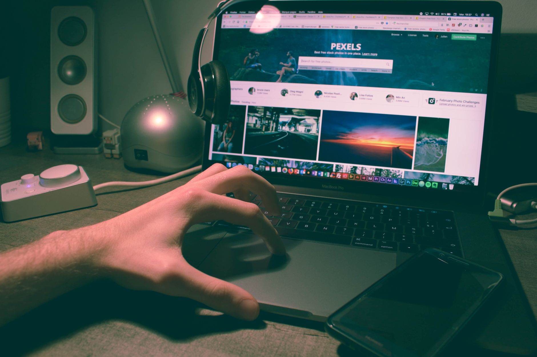 speed up wordpress website - Person browsing Pexels on a laptop with headphones and smartphone nearby.