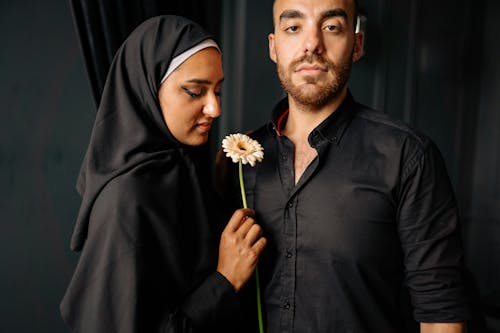 Man in Black Button Up Shirt Standing Beside Woman in Black Hijab