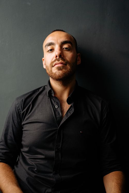 Free A confident man in a black button-up shirt against a dark background. Stock Photo