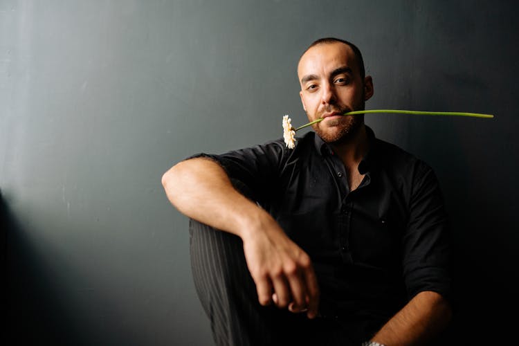 Man In Black Long Sleeves Biting A Flower