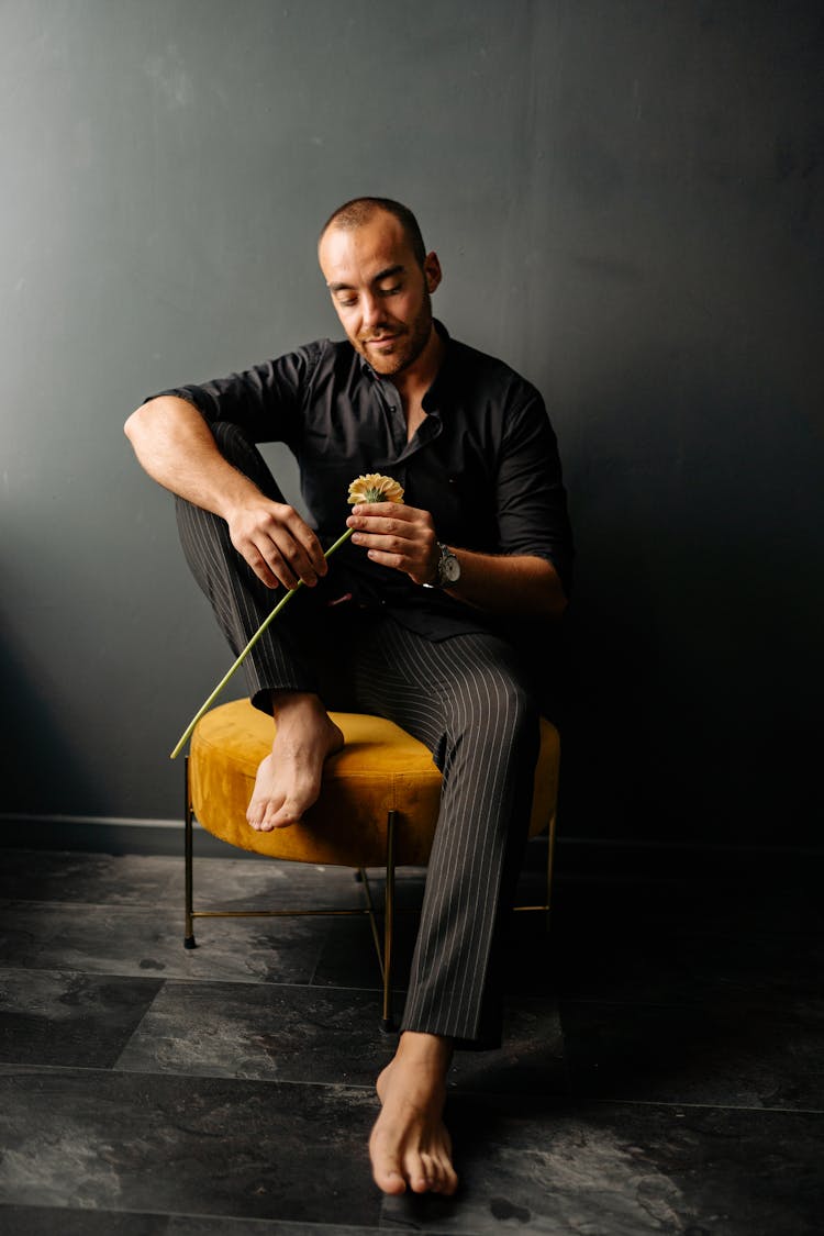 Man Sitting On Chair While Holding A Flower