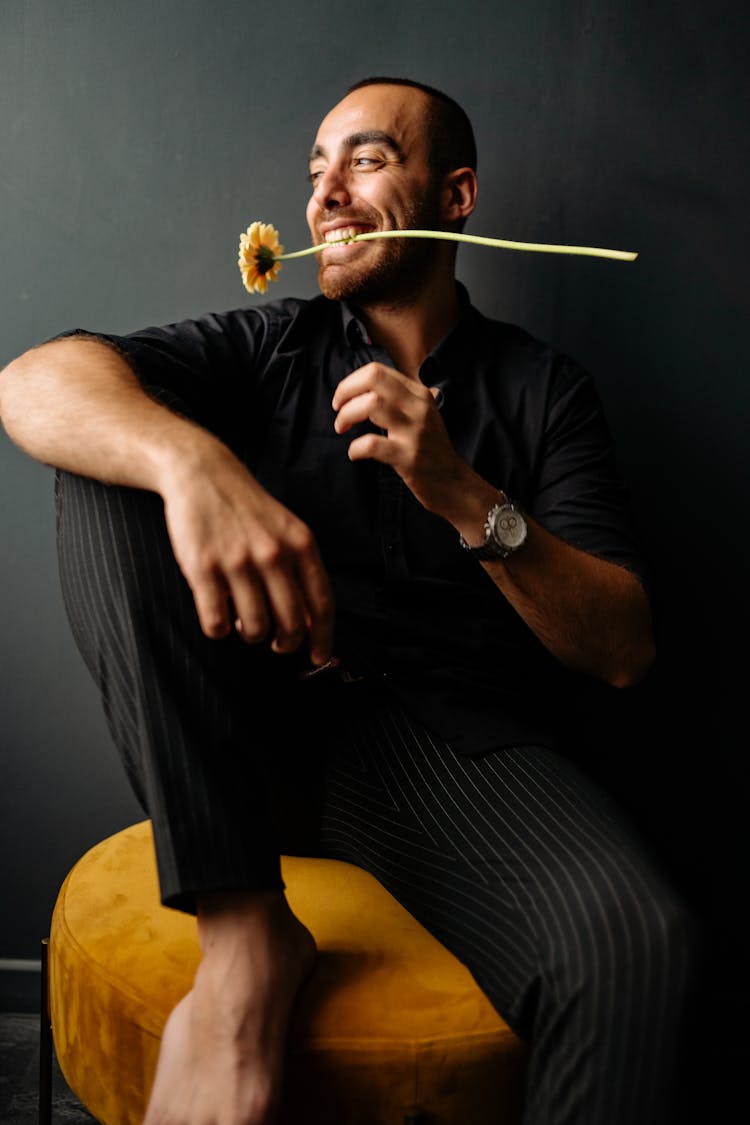 Man Biting A Flower While Sitting On A Chair 