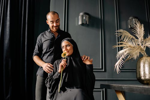 Smiling Man in Shirt Standing behind Sitting Woman in Abaya