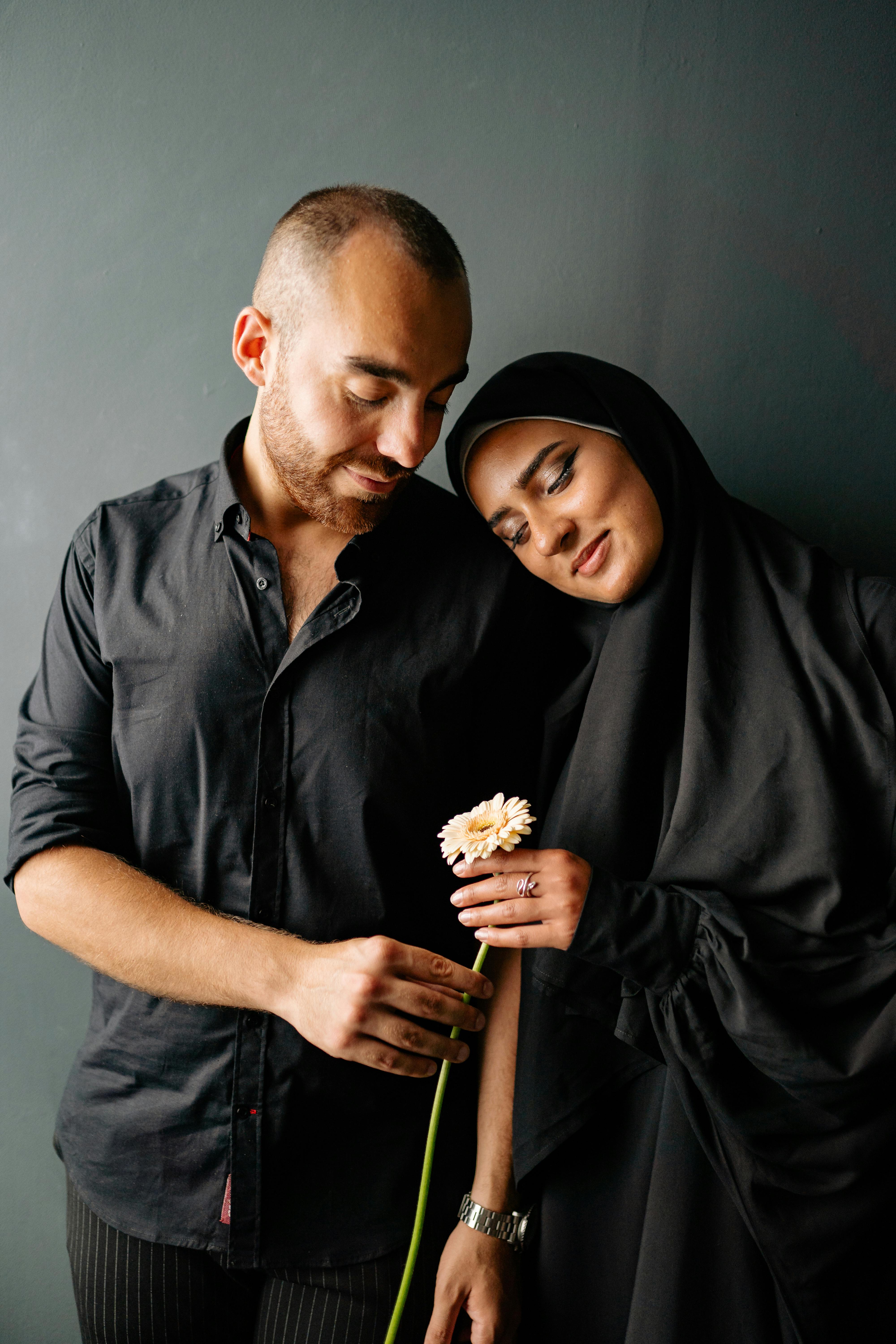 A beautiful couple in traditional attire sharing a tender moment holding a flower.