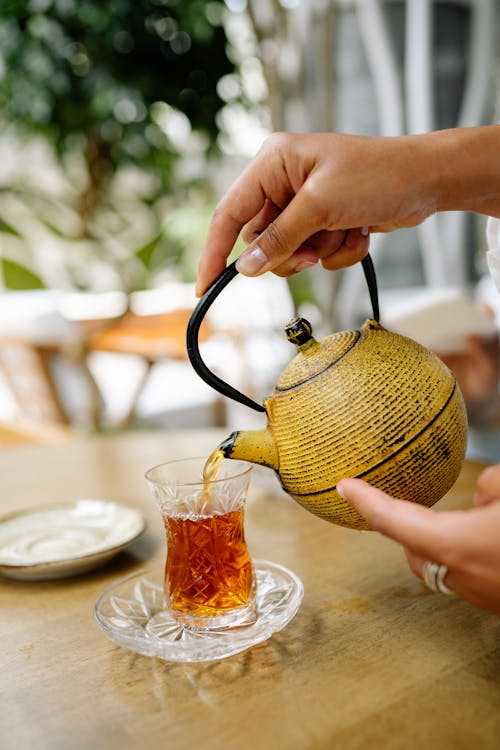 Free A Person Pouring Tea in a Tea Cup Stock Photo