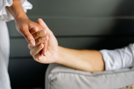 Close-up of a couple holding hands, symbolizing love and connection indoors.