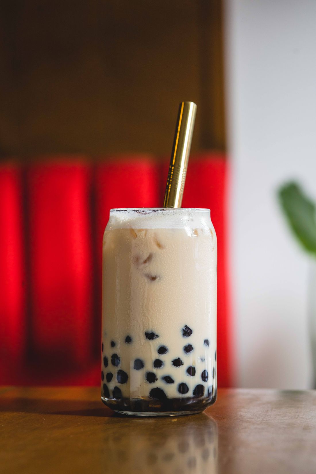 Logo-free iced milk tea in a glass with tapioca pearls and a gold straw