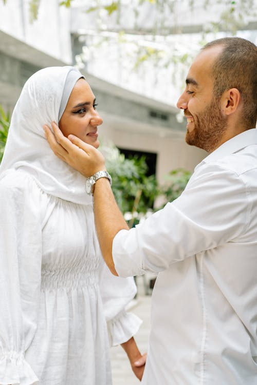 A Couple in White Clothing Looking at Each Other