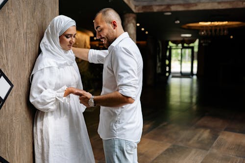 A Man Holding a Woman's Hand Leaning on a Wooden Wall