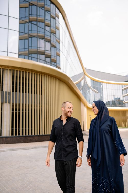 Free Smiling couple in traditional wear walking outdoors in an urban modern setting. Stock Photo
