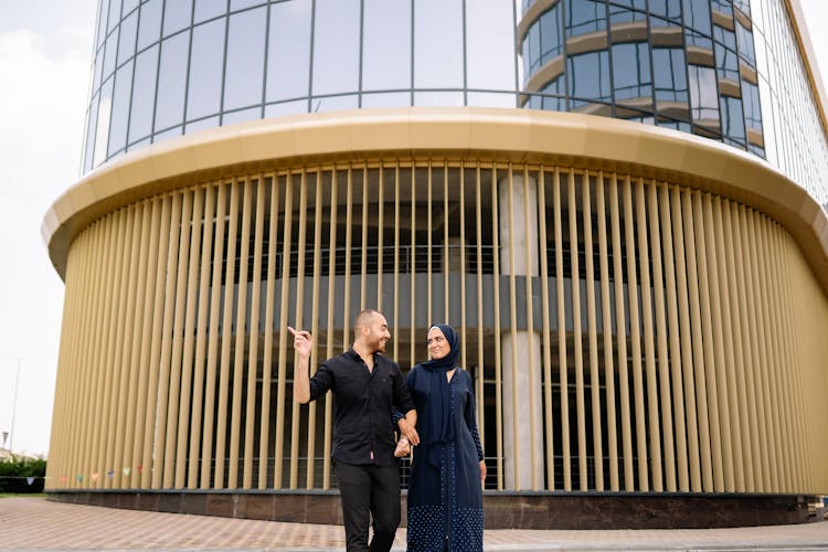 A Couple Walking In Front Of A Building