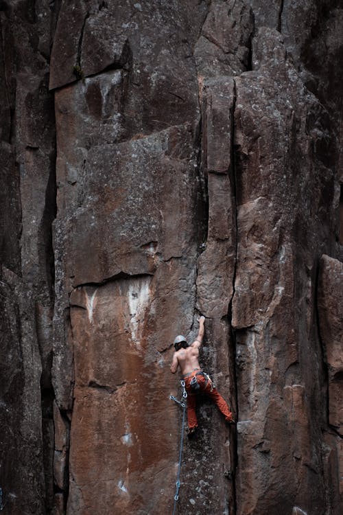 Free A Shirtless Man Climbing a Mountain Rock Stock Photo