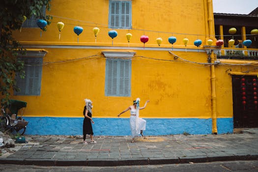Two women in traditional masks dancing under colorful lanterns in Hoi An.