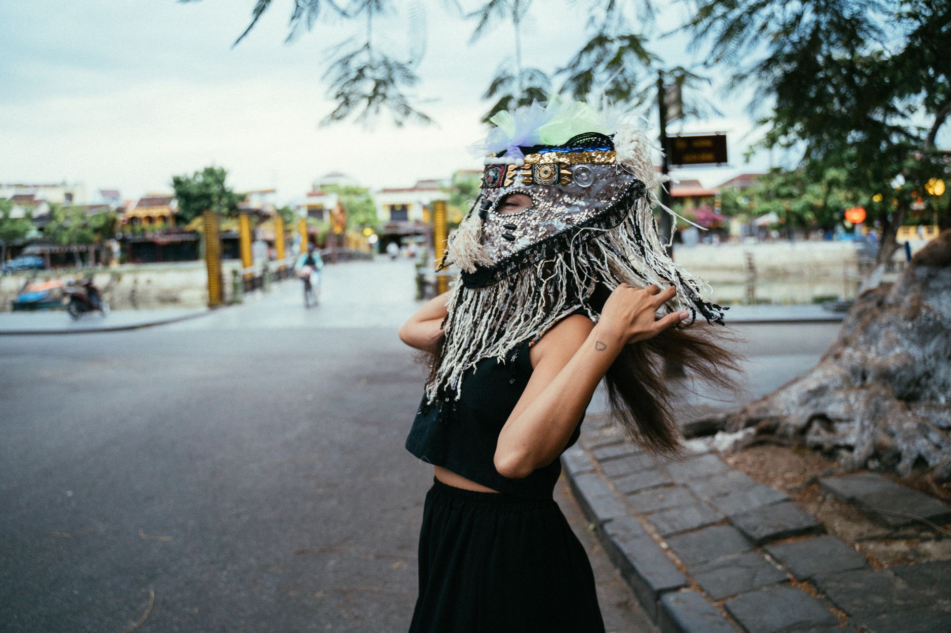 Woman in Black Sleeveless Top Wearing a Festival Mask