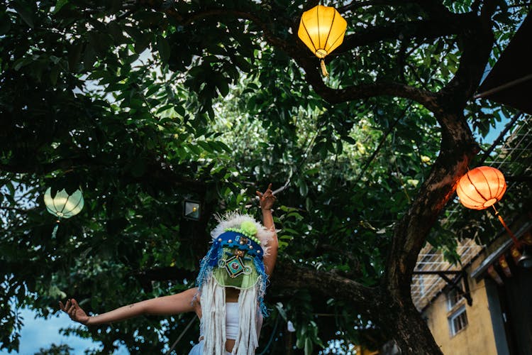 A Person In An Ethnic Mask Dancing Under Paper Lanterns