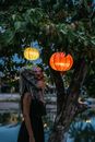 Woman in Black Dress Standing Near Orange Lantern