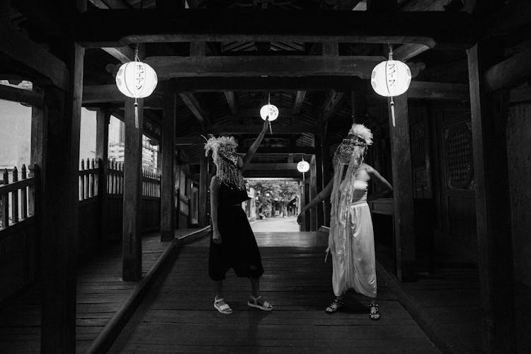 People In Ethnic Masks Standing In A Footbridge With Paper Lanterns