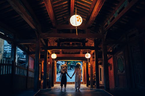 People in Ethnic Masks Holding Hands under Paper Lanterns