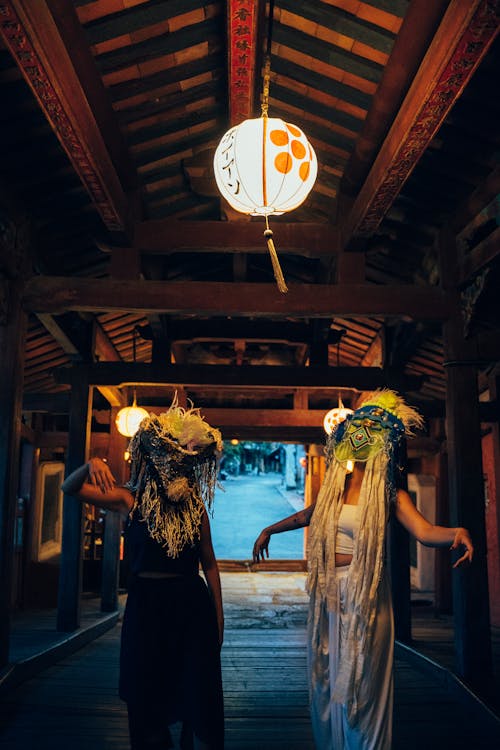 People in Ethnic Masks Dancing under a Paper Lantern
