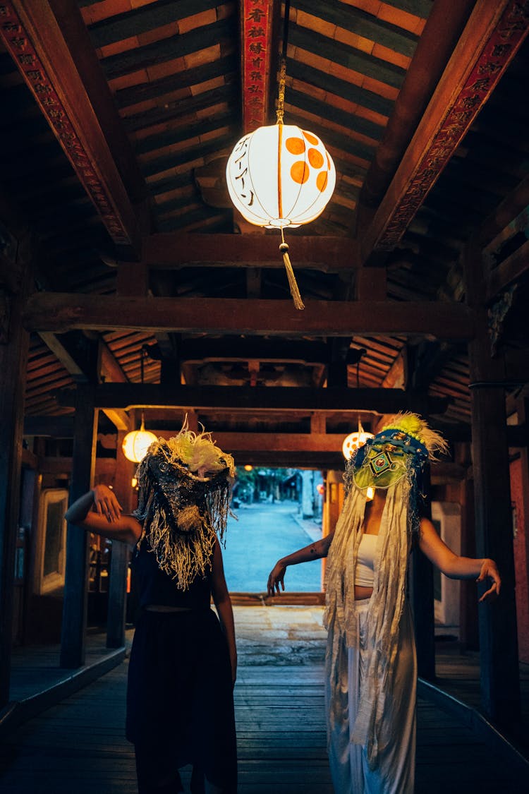 People In Ethnic Masks Dancing Under A Paper Lantern
