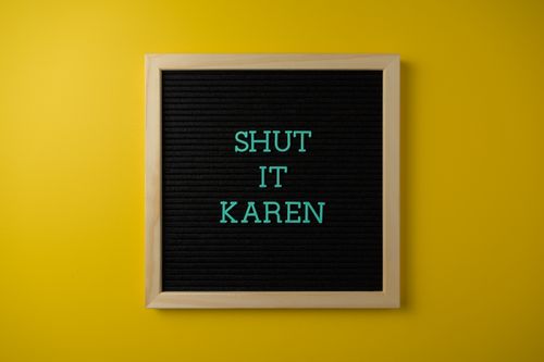 Free Square letter board with 'Shut it Karen' text on vivid yellow background. Stock Photo