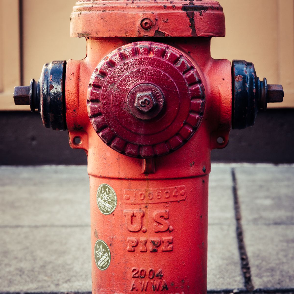 Detailed close-up of a vibrant red fire hydrant on a city sidewalk.