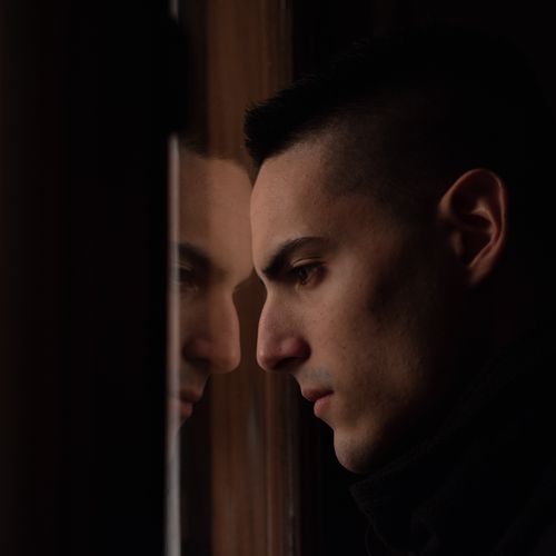 Free Thoughtful man gazing at reflection in a quiet moment indoors. Stock Photo