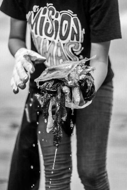 Grayscale Photo of Person Holding Wet Garbage