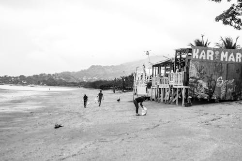 Grayscale Photo of a People Walking on the Sand