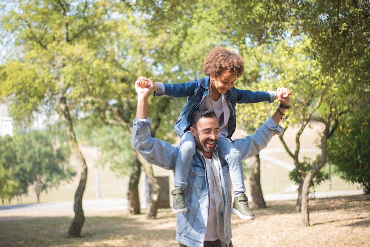 A Man Carrying A Child On His Shoulders