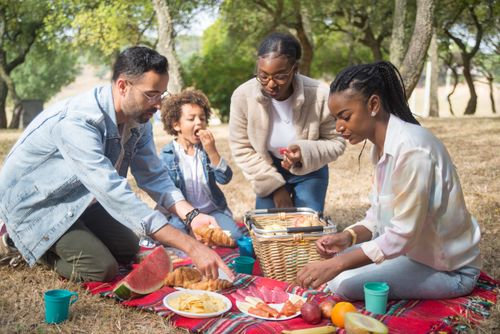 Free Family and friends enjoying a summer picnic with food and fun in a sunny park. Stock Photo