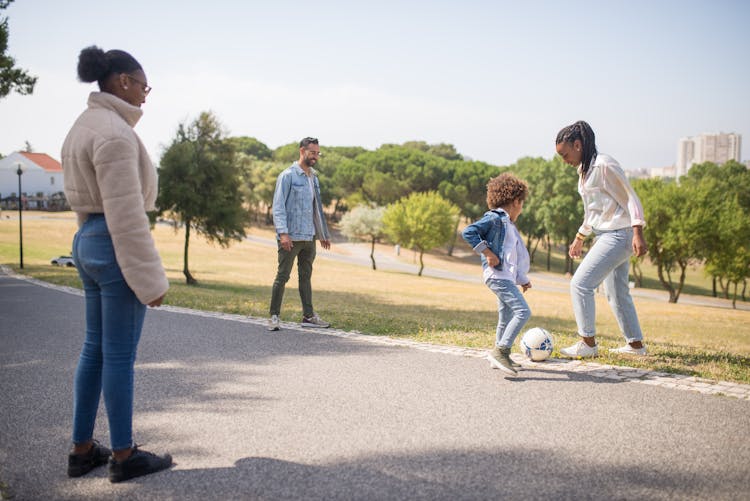 Women, Man And Boy Playing Soccer In Park